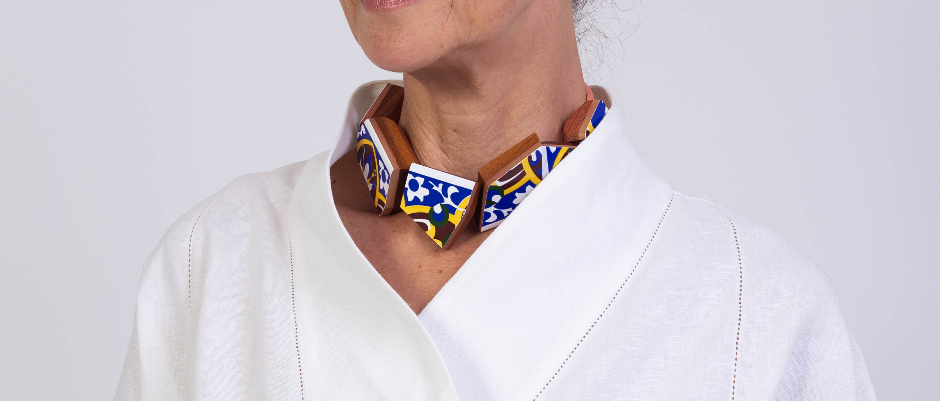 Cacos e tacos necklace in blue and yellow tiles, worn over white linen
